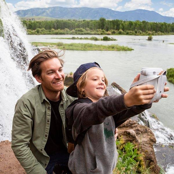 Father and child taking a selfie in front of waterfall