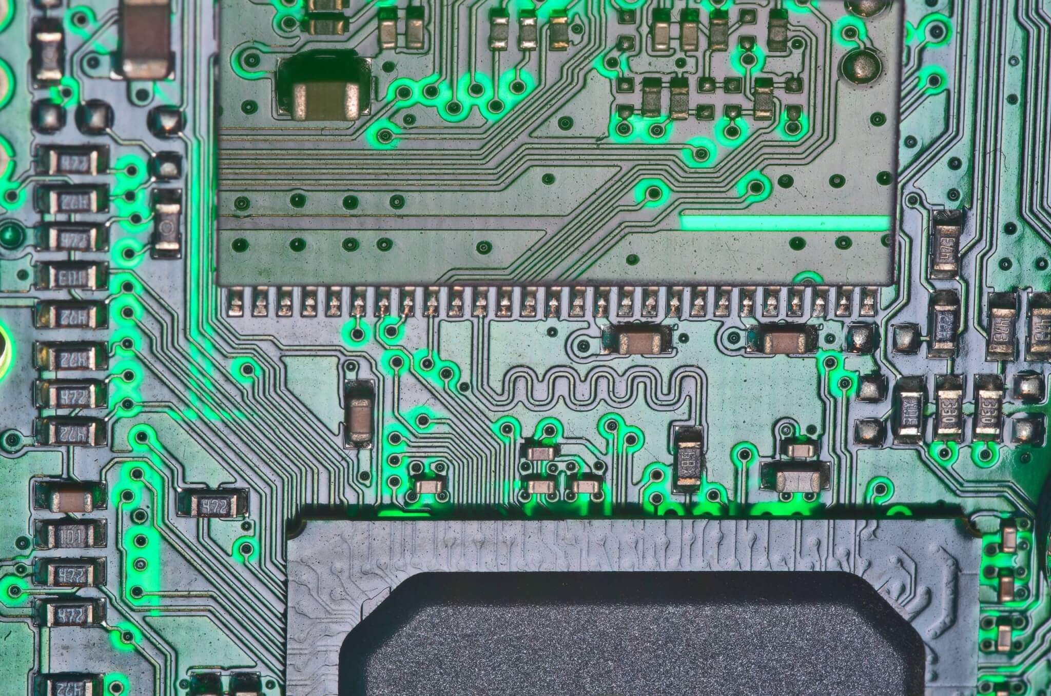 Close-up of a green circuit board with intricate copper traces and electronic components