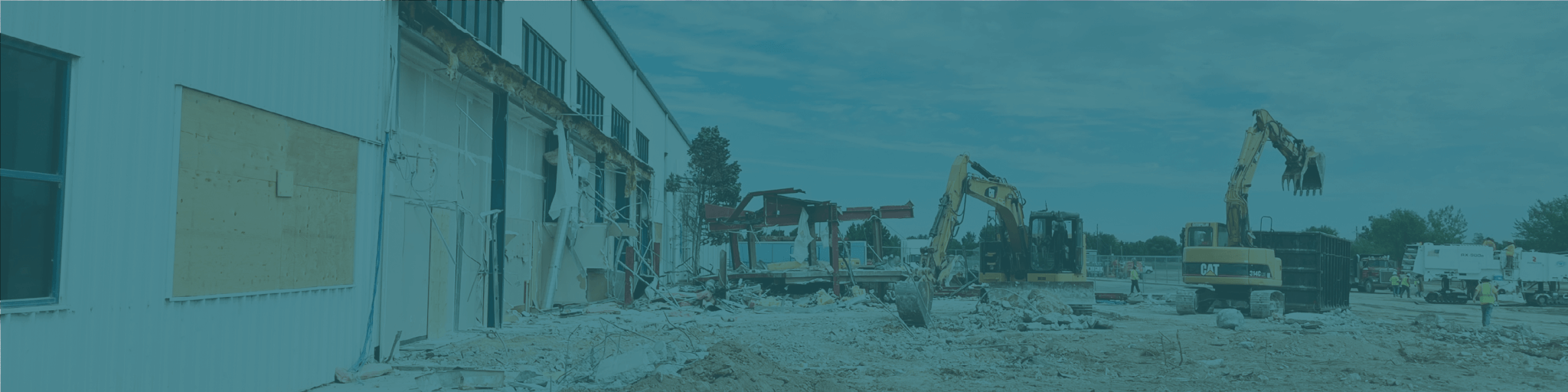 Construction site with two excavators demolishing a partially collapsed building