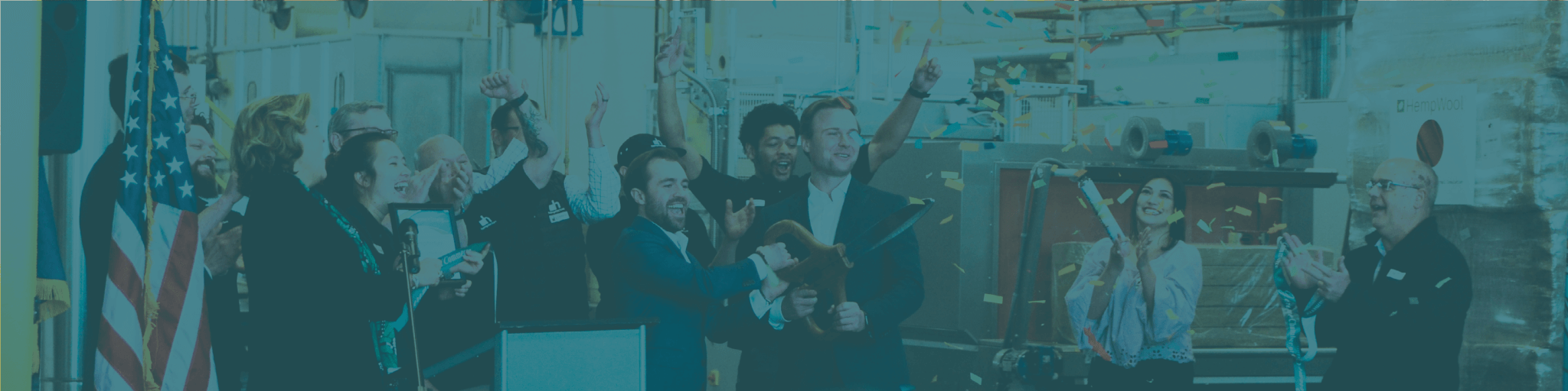 A group of people celebrate a ribbon-cutting ceremony with confetti and an American flag