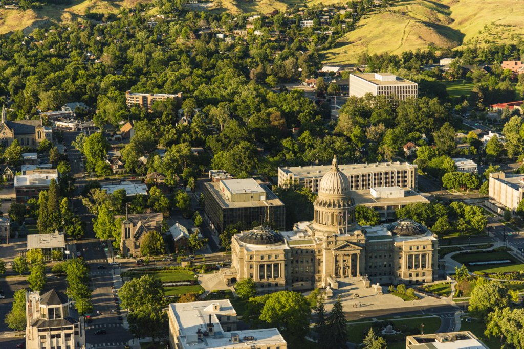 Aerial view of a city with a prominent domed building surrounded by greenery and modern architecture