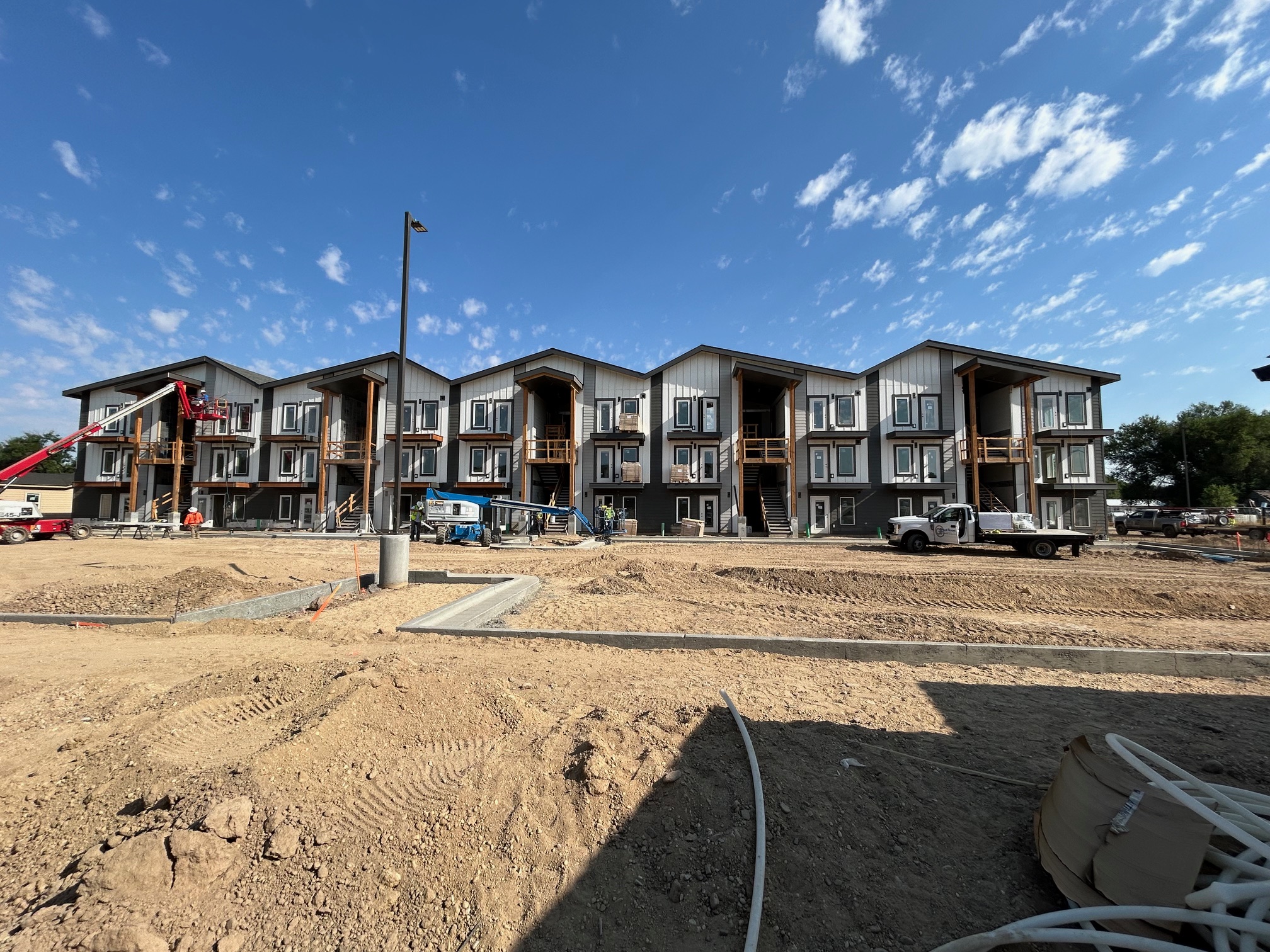 Construction site of a row of modern, multi-story residential buildings with cranes and workers
