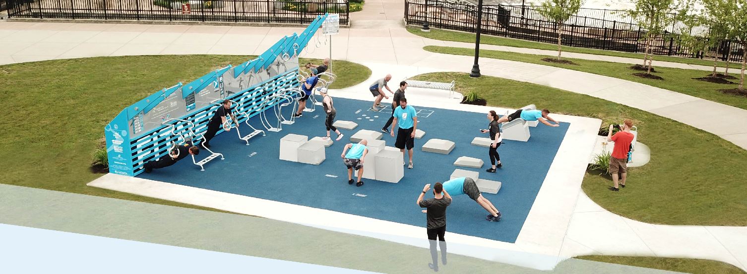 Outdoor fitness area with colorful equipment and people exercising in a park setting