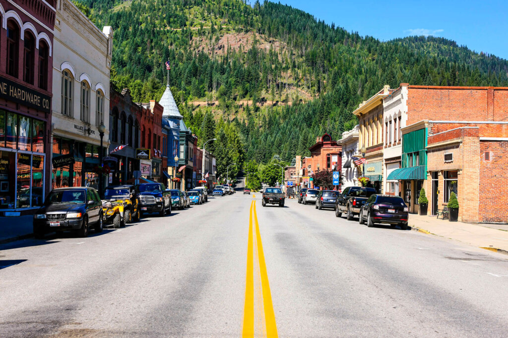 A picturesque mountain town street lined with colorful buildings and parked cars