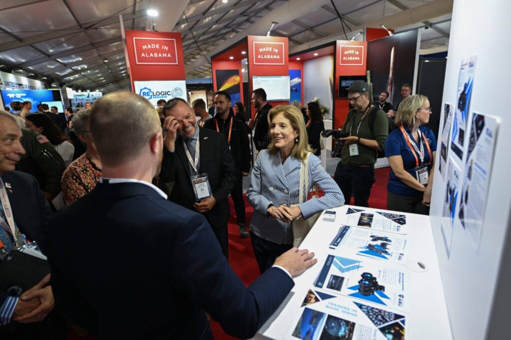 Attendees at a trade show engage in conversation around a display booth with promotional materials