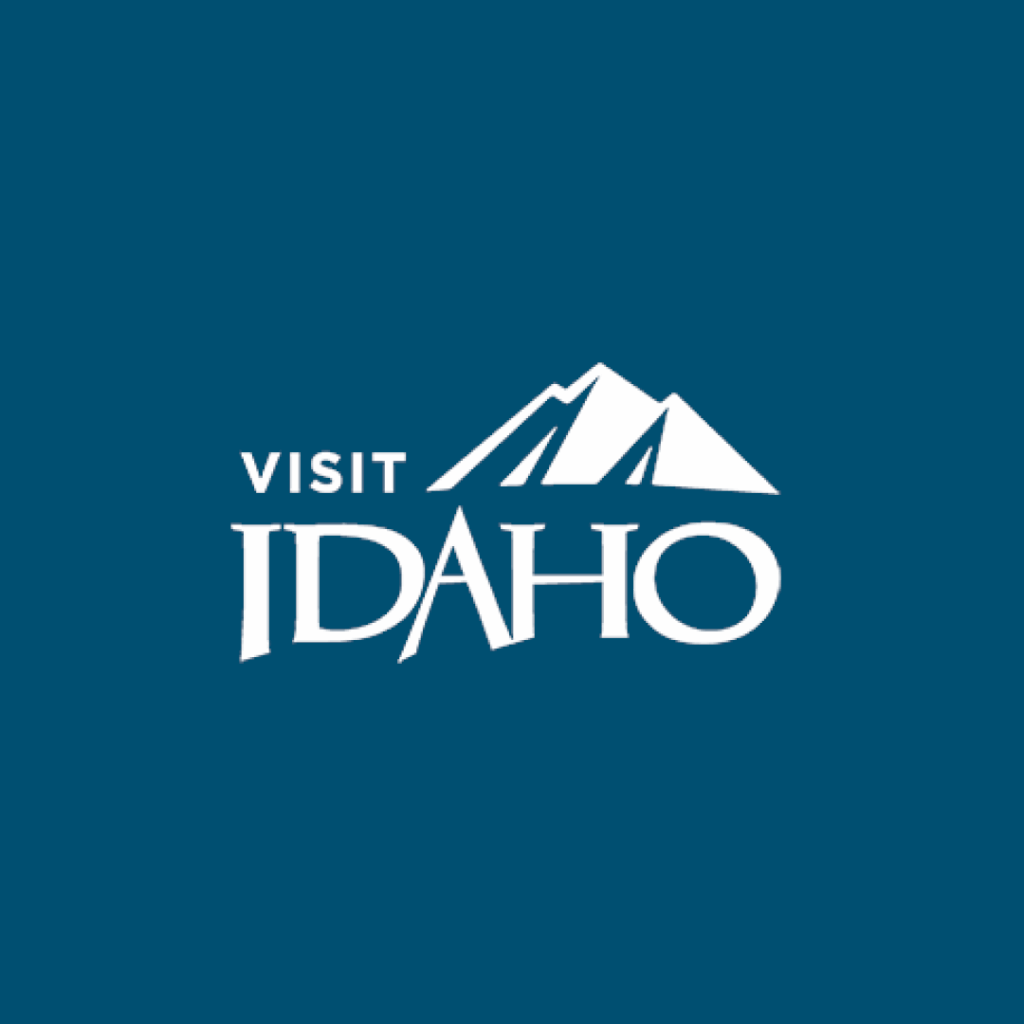 A stylized logo featuring a mountain range and the word 'IDAHO' in bold, inviting visitors to explore the state