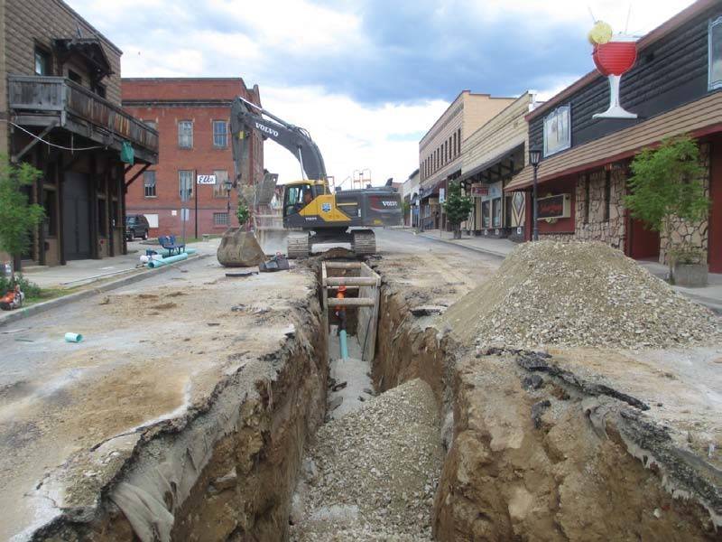 Construction site with excavator digging a trench in a small town street