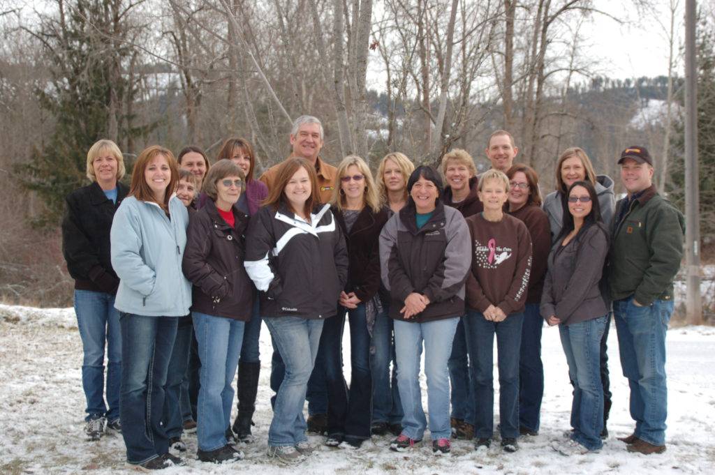 A group of people, dressed in winter clothing, stand together in a snowy outdoor setting
