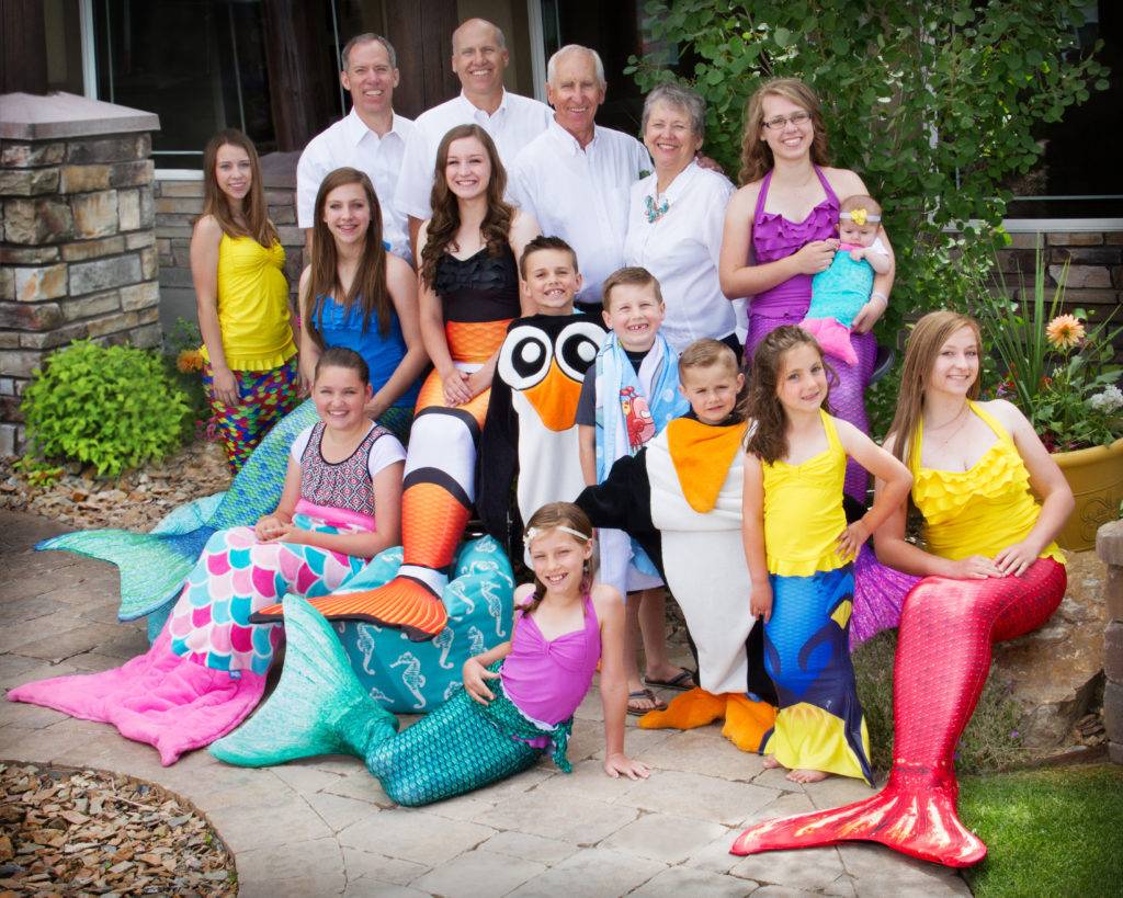 A large family dressed in colorful mermaid and sea creature costumes poses outdoors