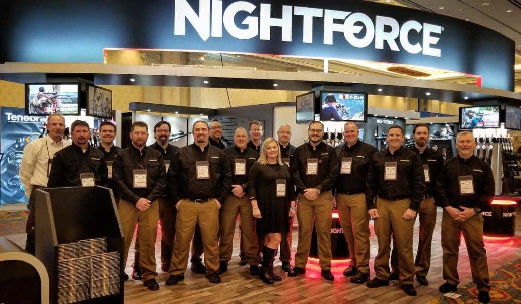 A group of Nightforce employees pose together at a trade show booth