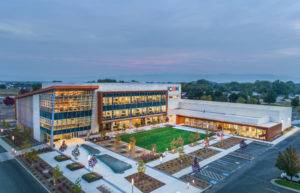 Modern office building with glass facade and green courtyard surrounded by parking lot