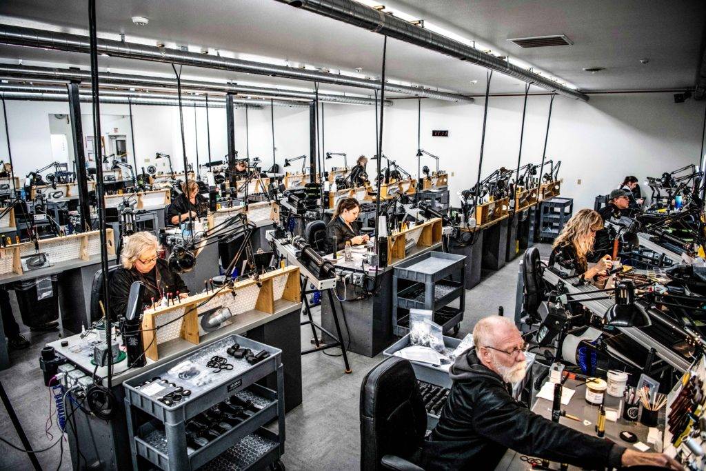 A large, well-lit workshop filled with people working at benches with tools and equipment