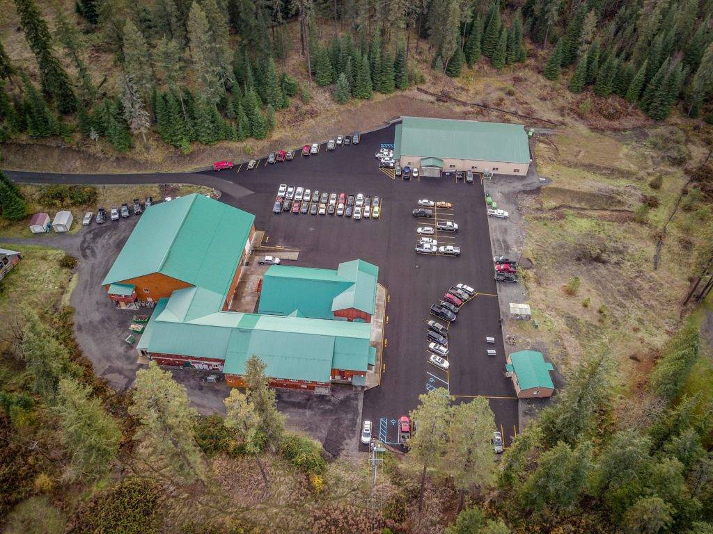 Aerial view of a green-roofed complex with parking lots surrounded by trees