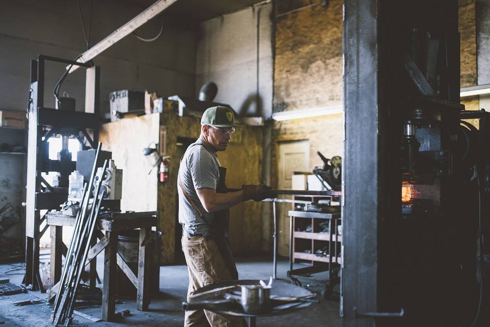 A skilled blacksmith works in a dimly lit workshop, shaping metal with traditional tools