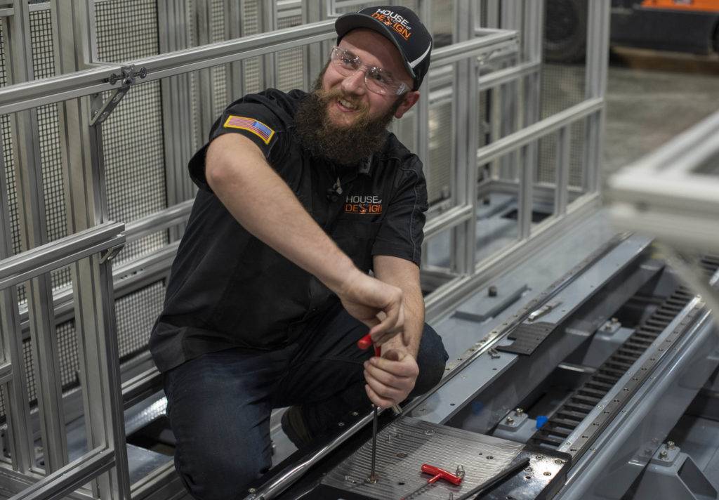 Bearded man in safety gear assembles metal parts in industrial setting
