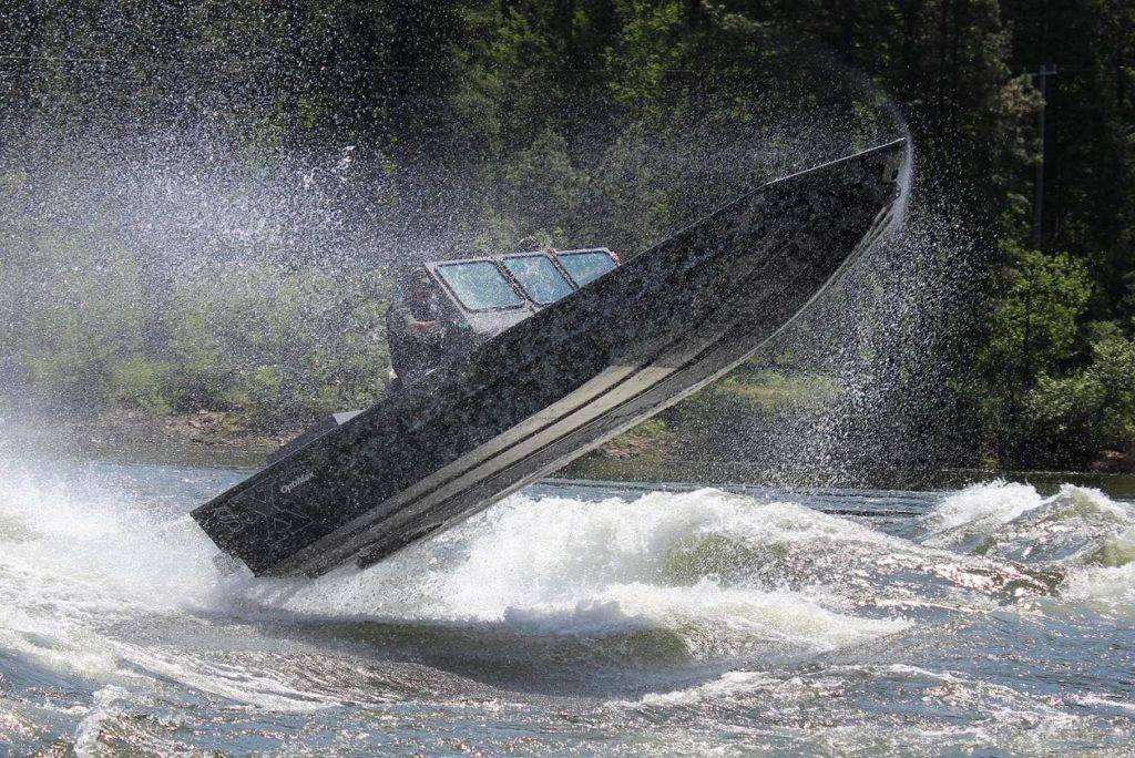 A speedboat with a person inside is dramatically launching into the air over rough waters