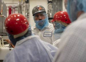 Workers in protective gear gather around a machine in a food processing facility