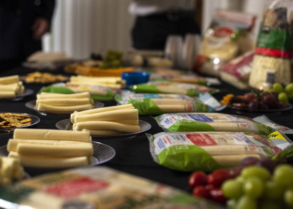 A buffet table with various cheeses, crackers, grapes, and tomatoes