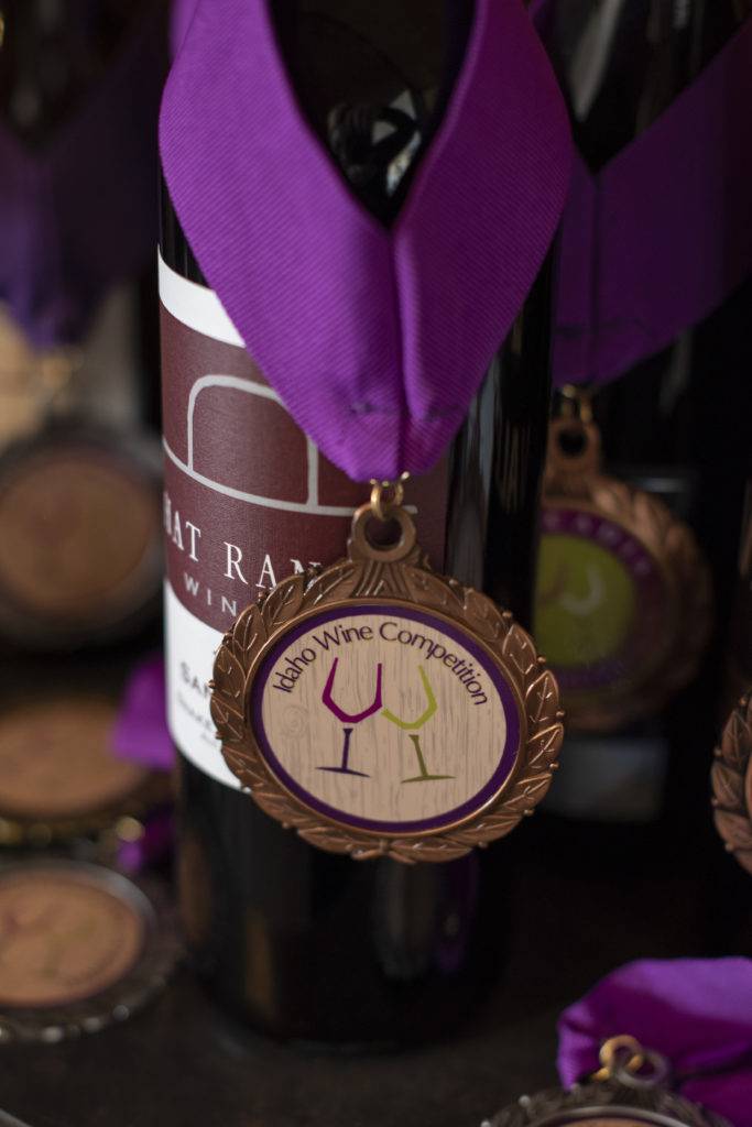 A wine bottle with a purple ribbon and bronze medal from the Idaho Wine Competition