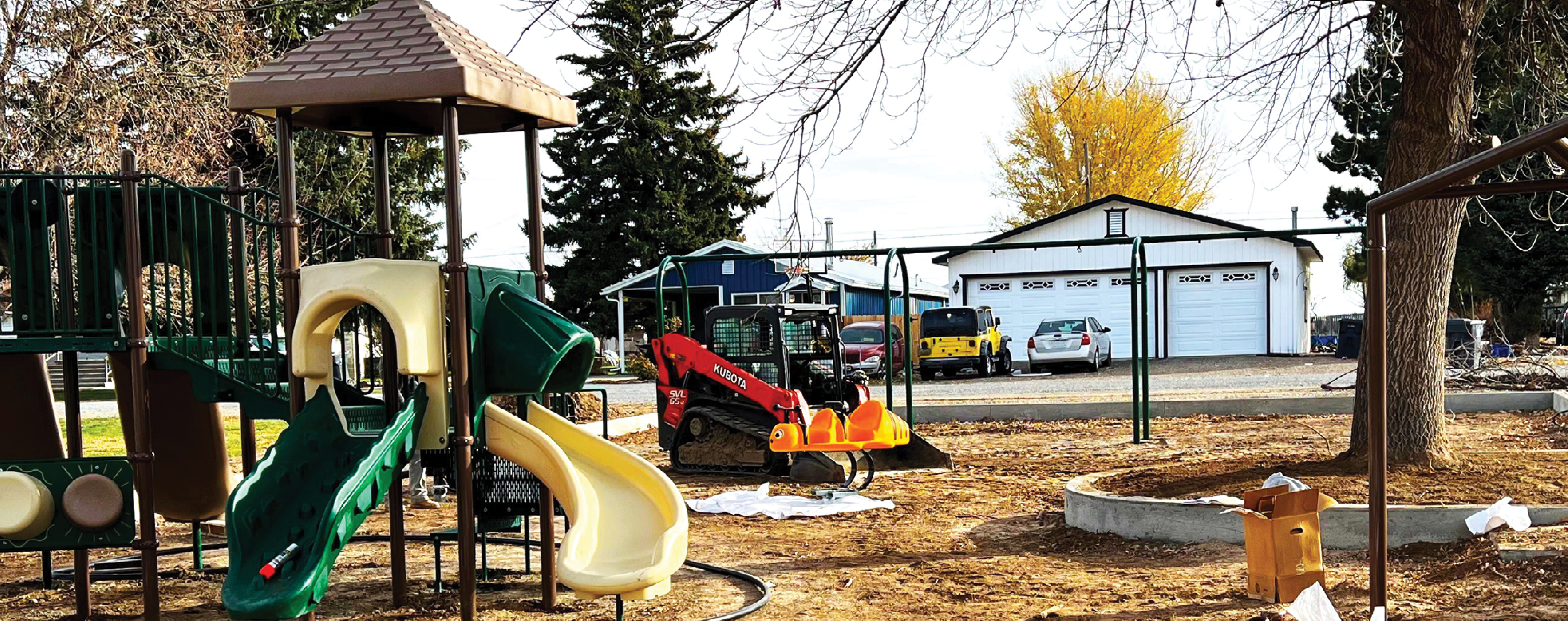 A construction site with a partially built playground, including slides and a swing set