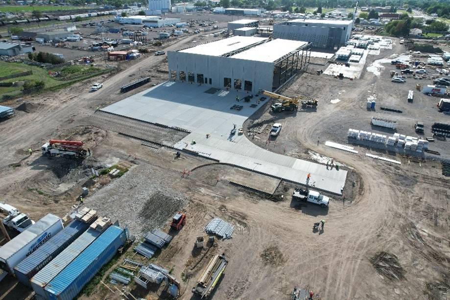 Aerial view of a large construction site with multiple buildings, cranes, and vehicles