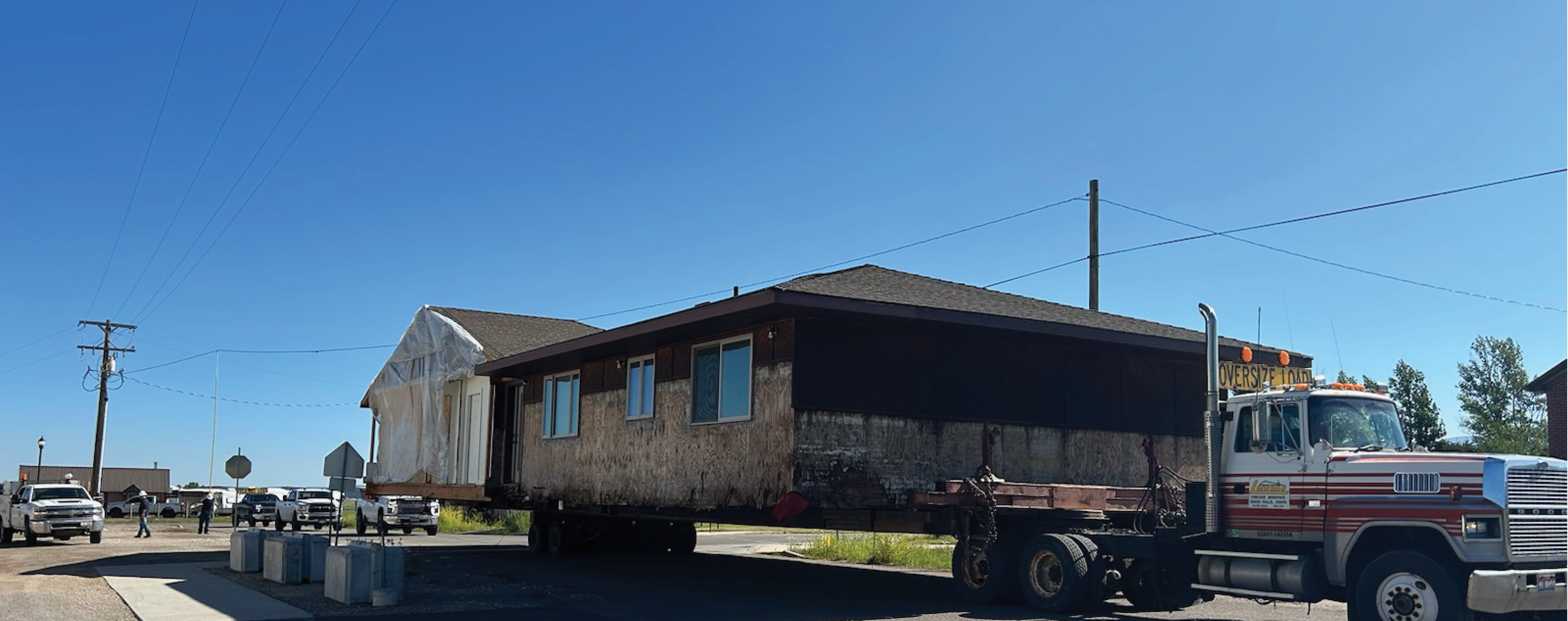 A large truck transports a prefabricated house on a sunny day