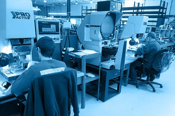 Workers operate precision machinery in a well-lit industrial workshop