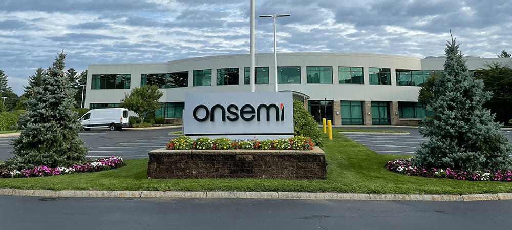 A white van is parked in front of a modern office building with a prominent 'onsemi' sign