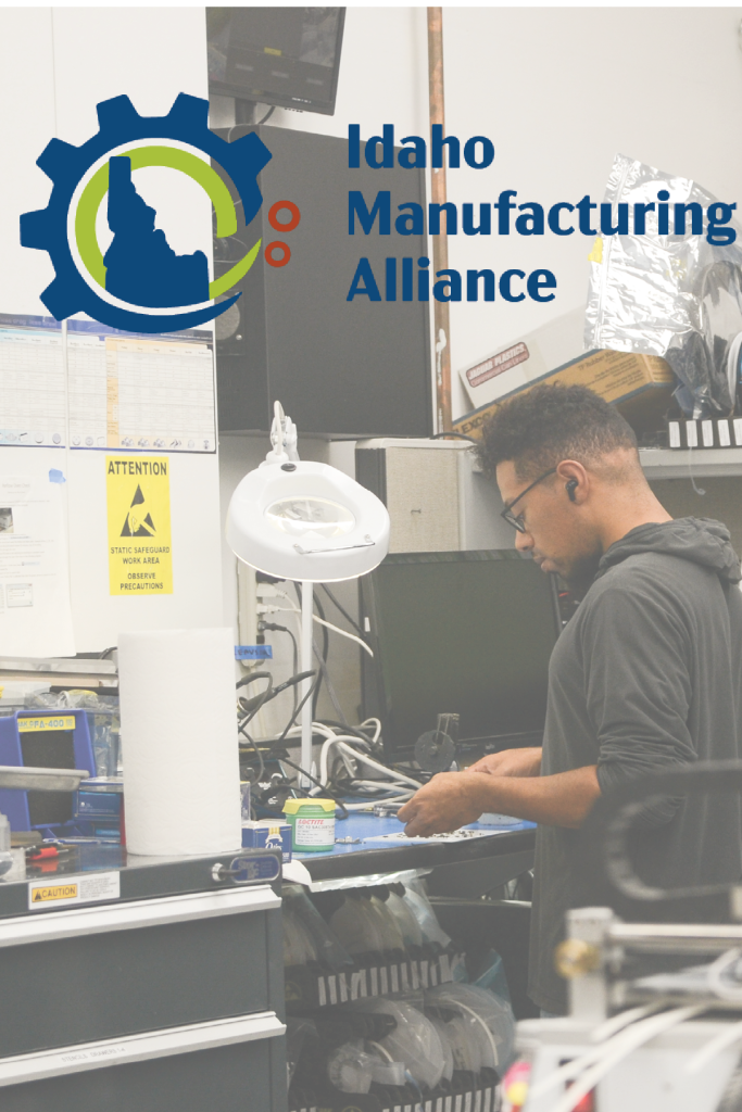A man wearing glasses and a hoodie is working on electronics in a cluttered workshop