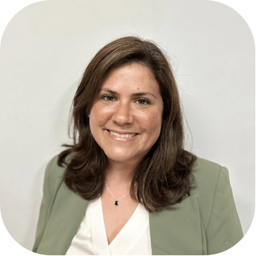 A smiling woman with shoulder-length brown hair wearing a green blazer and white shirt