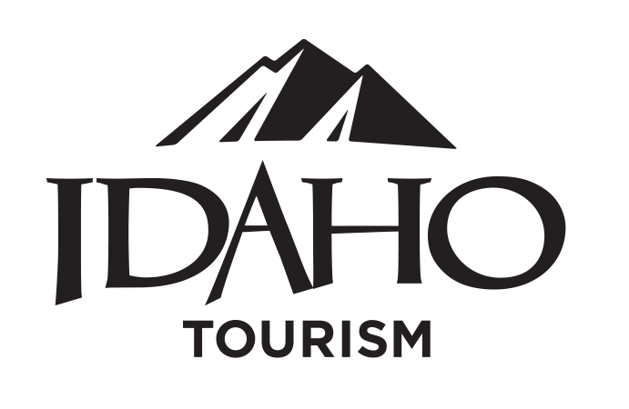 A stylized logo featuring a mountain range above the word 'IDAHO' with 'TOURISM' below