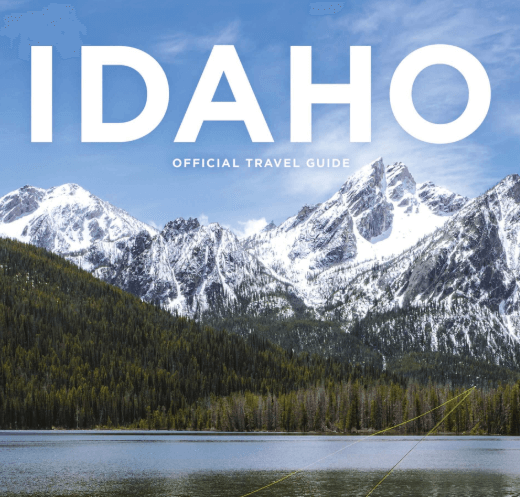 A serene lake surrounded by snow-capped mountains and lush green forests in Idaho